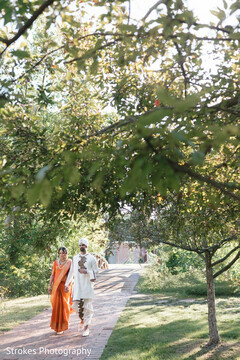 Couple's Radiant Walk in a Lush Garden, Vibrant Orange Sari & White Kurta
