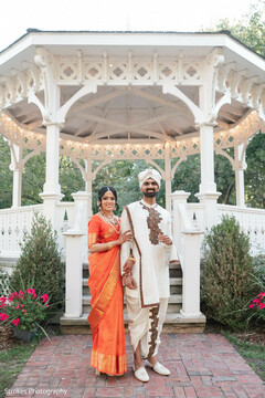 Vibrant Orange Sari & White Dhoti Kurta Against a Charming Gazebo