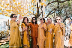 Women in Yellow Attire Pose Under Marigold Garlands