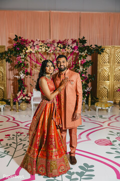Vibrant Peach & Red Couple's Portrait with Floral Arch Decor