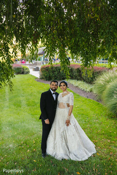 Elegant Couple Poses Under Lush Greenery in White and Black Attire