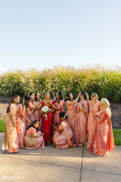 Bride in Red Lehenga with Bridal Party in Peach Saris
