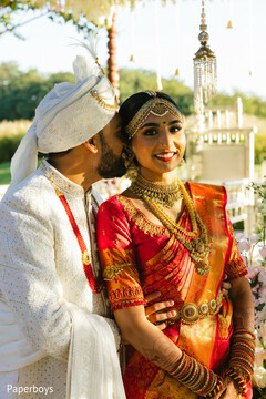 Groom Kisses Bride's Cheek in Red and Gold Sari