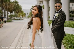 Bride in Backless White Gown Looks Over Shoulder with Groom in Tuxedo
