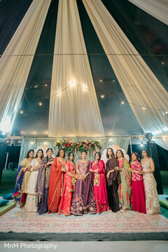 A bride poses with her bridal party under a striped tent