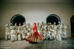 Bride in Red Lehenga Poses with Groomsmen in Cream Kurtas and Teal Turbans