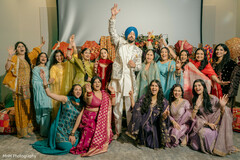 Groom in Cream Sherwani and Blue Turban Waves with Bridal Party in Colorful Attire