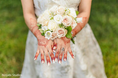 Bride's Hands Adorned with Mehndi Holding a Bouquet of White and Blush Roses