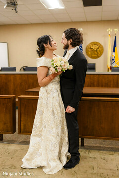 Bride and Groom Share a Loving Glance in Elegant Off-White and Gold Attire