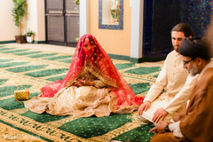 Bride Veiled in Red and Gold Seated Beside Groom and Man in Brown Robe