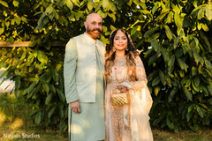 Couple in Light Gold and Mint Green Attire Against Lush Greenery