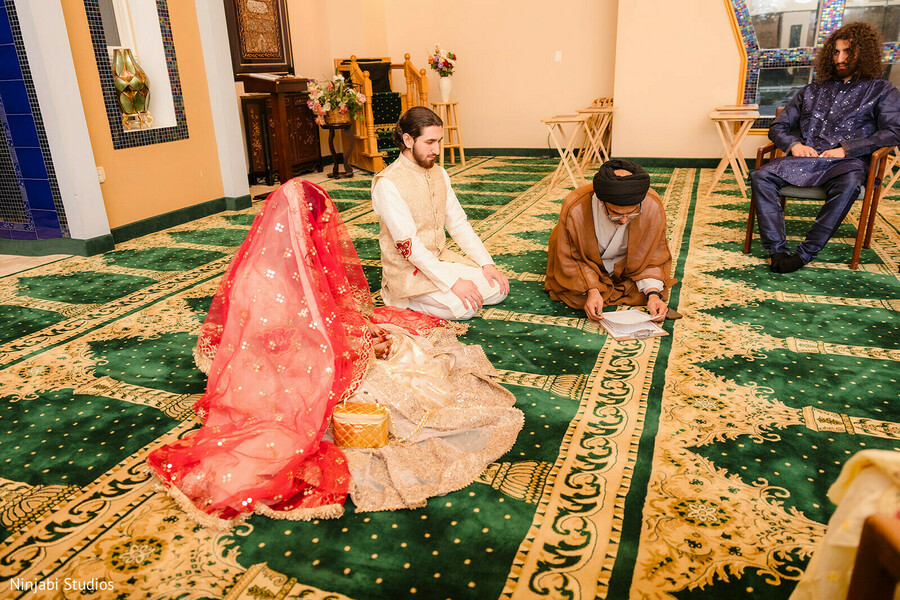 ceremony,groom,red dupatta,cream sherwani,green carpet,gold patterns,traditional attire