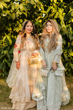 Two Women in Embroidered Anarkali Suits with Maang Tikka Posing Outdoors
