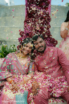 Joyful Couple Bathed in Pink Petals During a South Asian Wedding