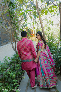 Couple in Pink and Multi-Colored Embroidered Attire Walking in a Garden
