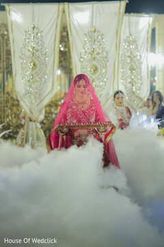 Bride in Pink Lehenga Carries Tray Amidst Wedding Decor