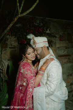Bride in Pink Lehenga and Groom in Ivory Sherwani Embrace