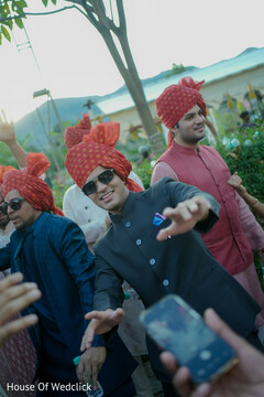 Men in Red Turbans and Dark Jackets Dancing Outdoors