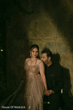 Couple Poses Against Stone Wall in Embellished Gown and Dark Suit