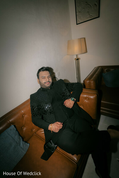 Groom in Black Sherwani Lounging on a Brown Couch