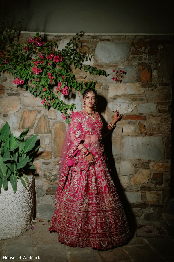 Bride in Pink Lehenga with Gold Embroidery Against Stone Wall