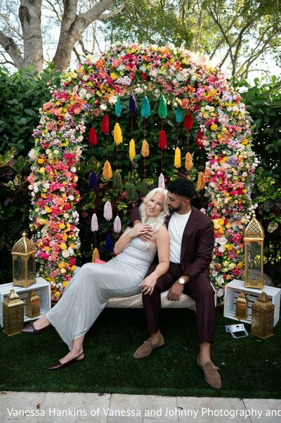 couple portraits,floral arch,colorful decor,photo session,outdoor setting,burgundy suit,silver gown,decorative lanterns,white wooden boxes