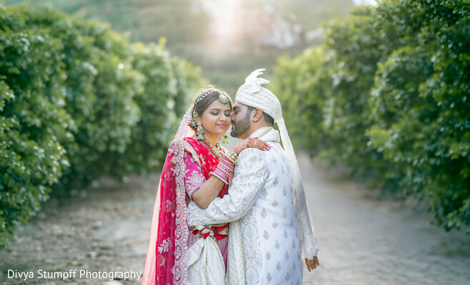 south asian wedding,couple portrait,sunset photo session,pink lehenga,white sherwani,orchard wedding,bridal fashion,groom fashion,outdoor photography,romantic wedding photos