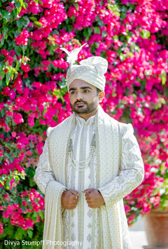 Groom's Elegant Ivory Sherwani Against Vibrant Pink Bougainvillea
