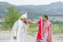Groom Kisses Bride's Hand Against Mountainous Backdrop