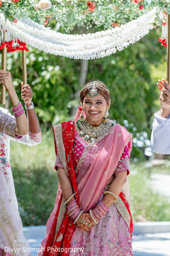 Joyful Bride's Entrance with Floral Archway and Pink Lehenga