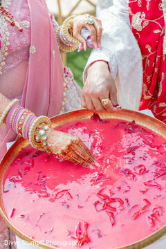 Hands Adorned with Bangles and Rings Dip into Pink Liquid