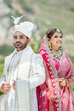 Regal Couple in Ivory Sherwani and Pink Lehenga with Emerald Accents