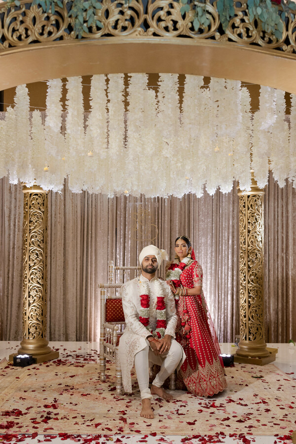 south asian wedding,red lehenga,white sherwani,floral canopy,wedding portraits,couple photo,wedding decor,detroit wedding,traditional attire,gold accents