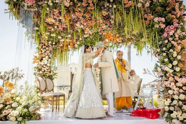 floral arch,wedding ceremony,floral decor,couple,bride,groom,lehenga,sherwani,mandap