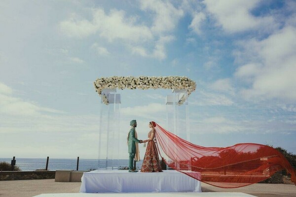 south asian wedding,outdoor ceremony,oceanfront mandap,red veil,floral decor,modern mandap,wedding ceremony,bridal fashion