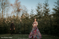 Woman in Vibrant Floral Lehenga Poses Outdoors with Man in Dark Kurta