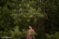 Bride in Multi-Colored Lehenga Amidst Lush Greenery