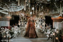 Bride in Brown and Gold Lehenga Amidst Opulent Floral Decor