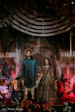 Couple Poses on Stage with Purple and Red Floral Decor