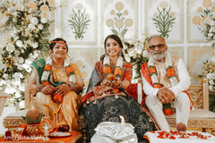 Bride Seated with Two Individuals Amidst Floral Decor