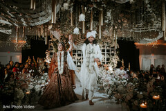 Couple Walks Down Aisle with Overhead Floral and Hanging Decor