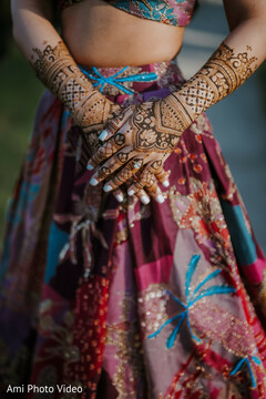 Intricate Bridal Mehndi on Hands Against a Patterned Lehenga Skirt