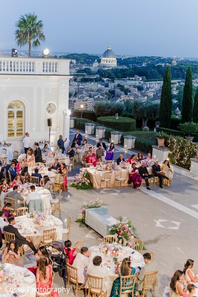 outdoor reception,floral decor,pink flowers,night event,wedding guests,elegant decor,city view