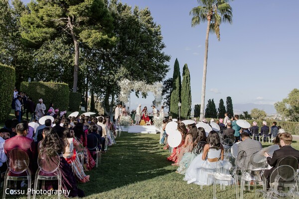outdoor wedding,ceremony,white floral arch,clear chairs,white parasols,wedding guests