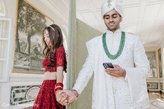 Bride in Red Lehenga and Groom in White Sherwani Holding Hands