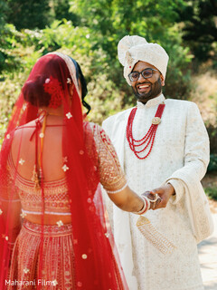Joyful Couple's First Look with Red Beaded Jewelry and White Sherwani