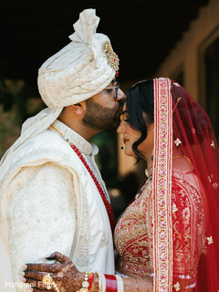 Intimate Bridal Portrait with Groom's Forehead Kiss and Red Veil