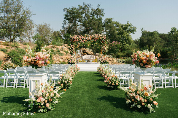 outdoor ceremony,floral decor,peach flowers,white chairs,wedding aisle,garden wedding,ceremony decor,floral backdrop