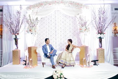 Beautiful indian coupl;e sitting on the white themed reception stage. Beautiful indian coupl;e sitting on the white themed reception stage.