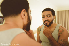 Indian groom looking himself in the mirror while getting ready Indian groom looking himself in the mirror while getting ready